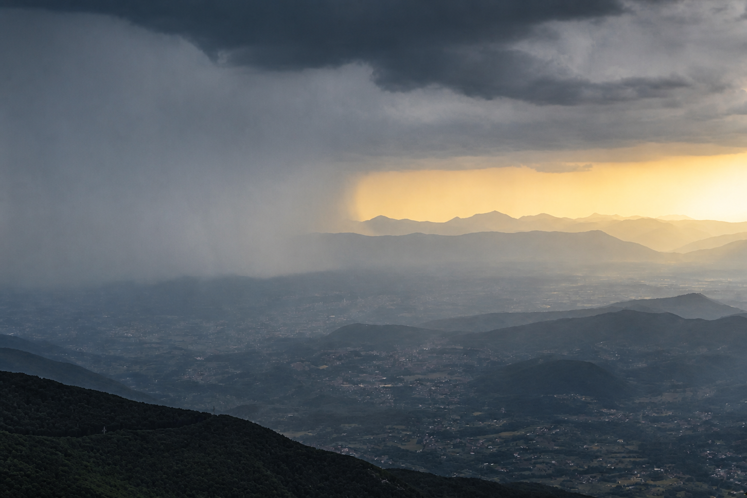 Pioggia sulle montagne e una zona di luce oltre le nuvole