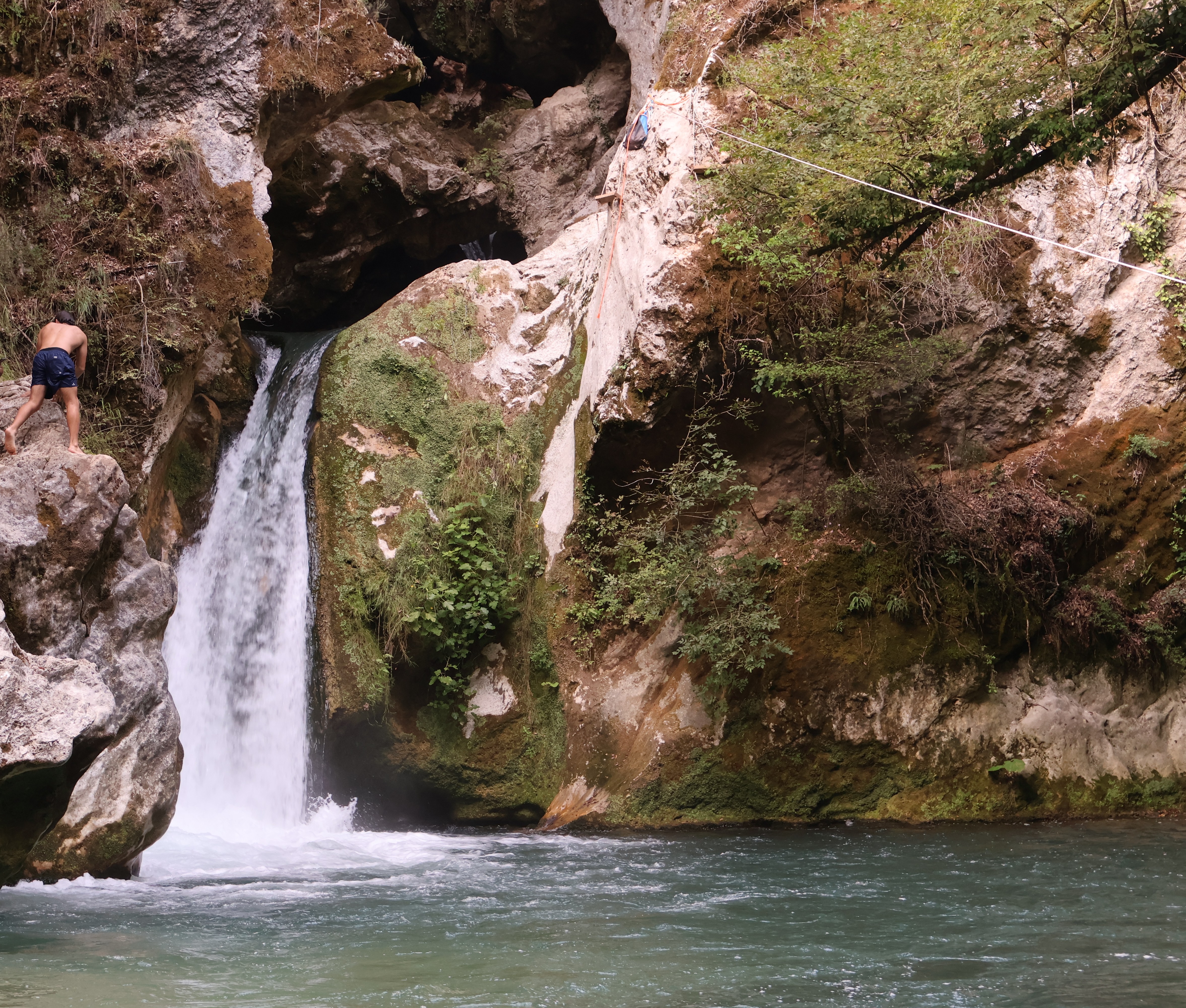 Una persona risale sulle rocce accanto a una cascata