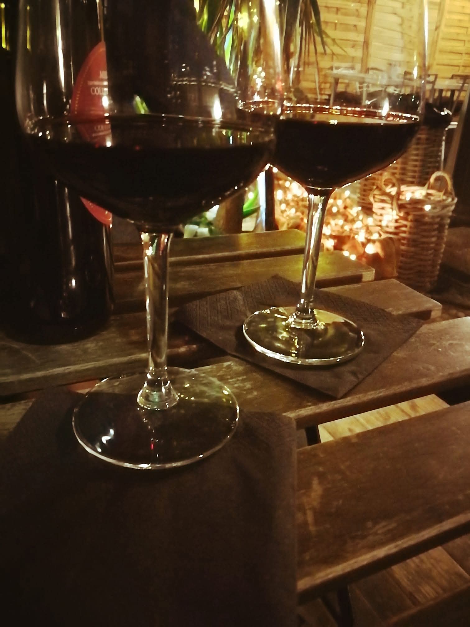 Due calici di vino su un tavolo di legno, illuminati dalla luce calda della sera